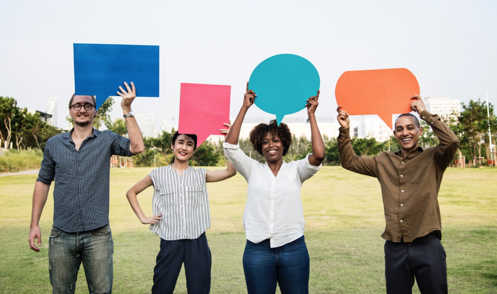 Four people holding different colored and shaped signs representing personalized communication. 