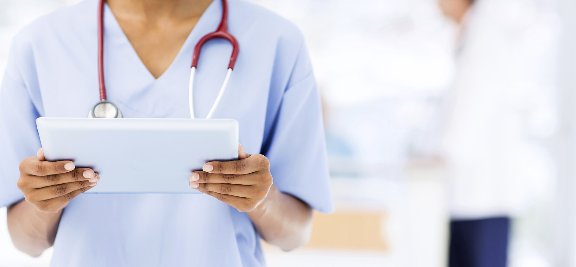 Image of a midsection of a person in a doctor's uniform with a tablet and a stethoscope. 